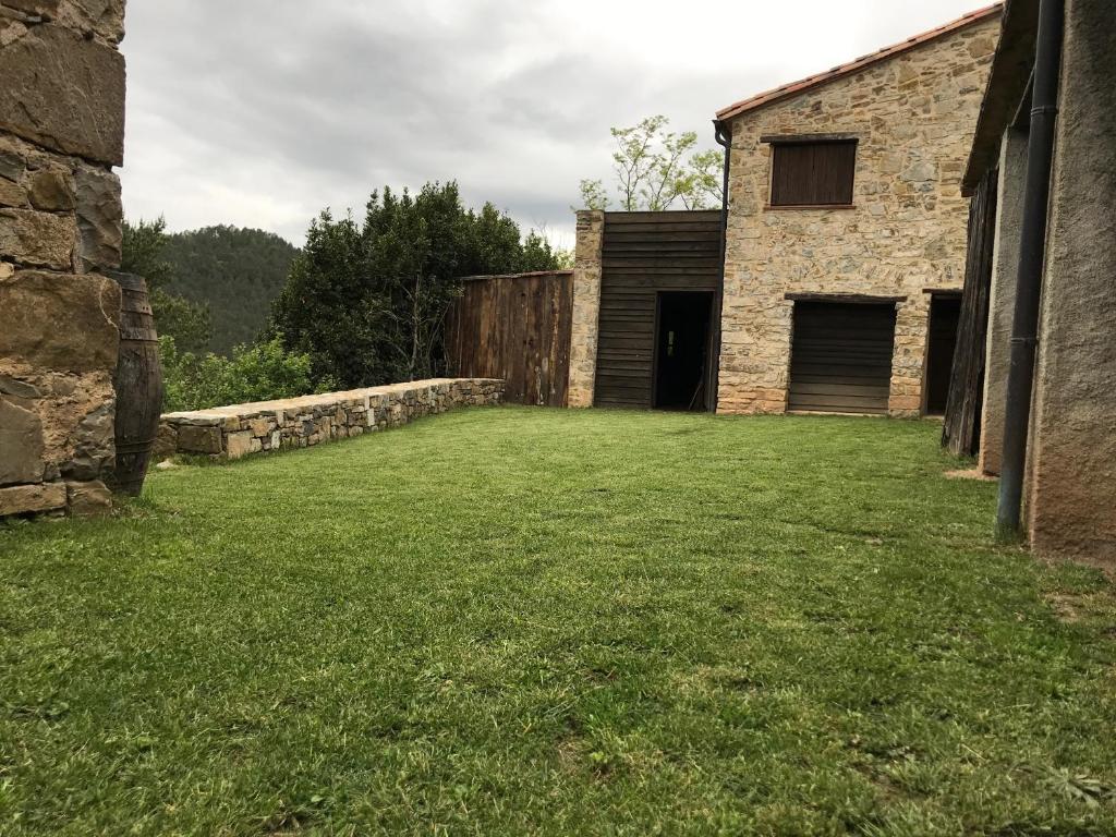 einen Hof mit einer Steinmauer und einem Gebäude in der Unterkunft Can Sau in Sant Joan de les Abadesses