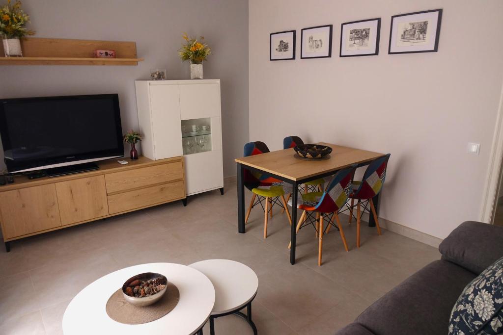 apartament dúplex "Alsina" في تريمب: غرفة معيشة فيها تلفزيون وطاولة وكراسي
