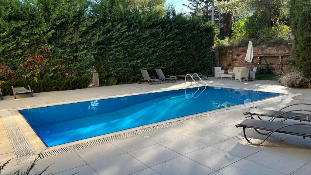 uma piscina com cadeiras e uma mesa em Dionisos luxury apartment em Atenas