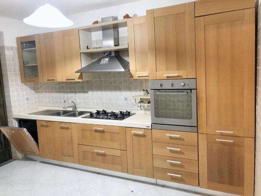 - une cuisine avec des placards en bois et une cuisinière dans l'établissement 3 bedrooms apartement with furnished balcony at Catelde, à San Giovanni