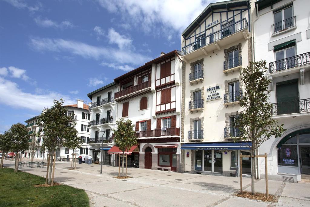 um edifício de apartamentos numa rua com árvores em frente em Hotel Le Relais Saint-Jacques em Saint-Jean-de-Luz