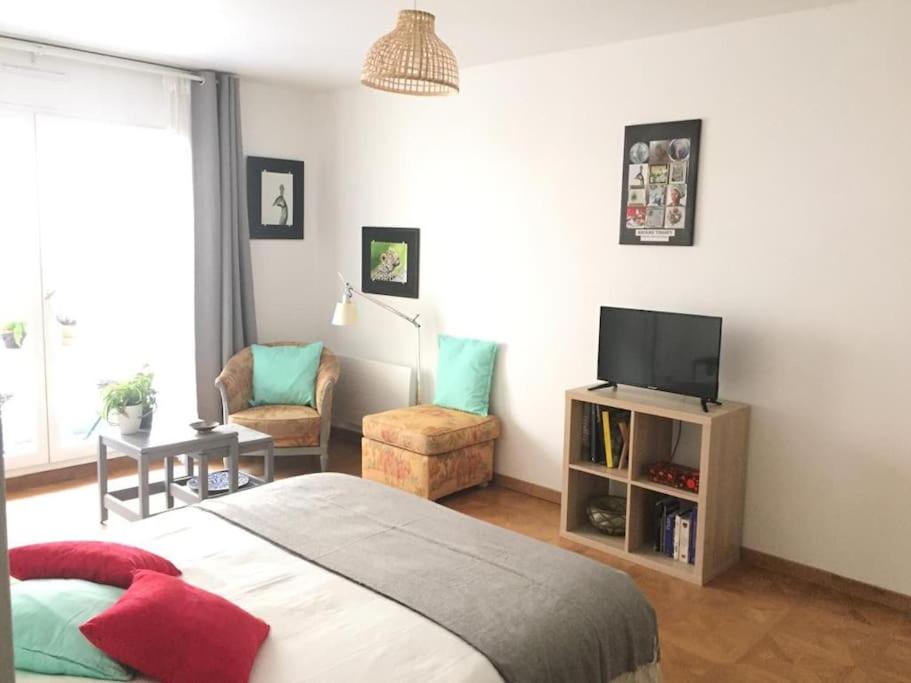 une chambre avec un lit, une télévision et une chaise dans l'établissement Studio centre-ville accès direct Paris, à Saint-Cloud