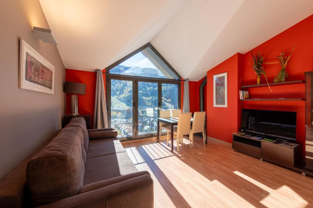 a living room with red walls and a couch and a table at Apartamento moderno bh aspen atico con vistas in El Tarter