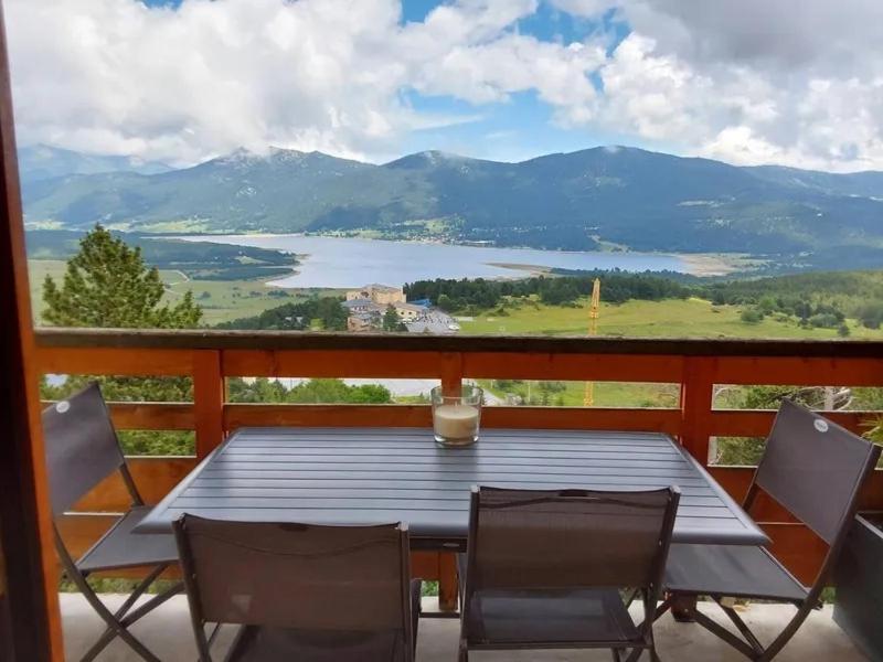 une table et des chaises sur un balcon avec vue sur un lac dans l'établissement Cosy Wood - Appt vue lac et montagne, aux Angles