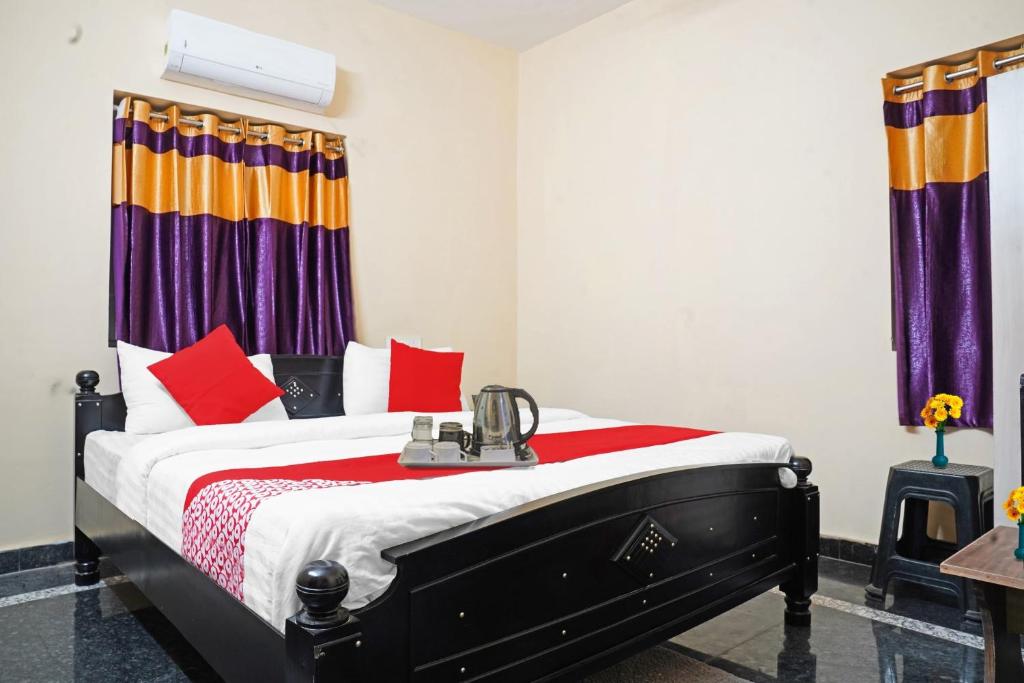 sypialnia z łóżkiem z czerwonymi i pomarańczowymi poduszkami w obiekcie OYO NSK Mahanadu Extension w mieście Gunadala