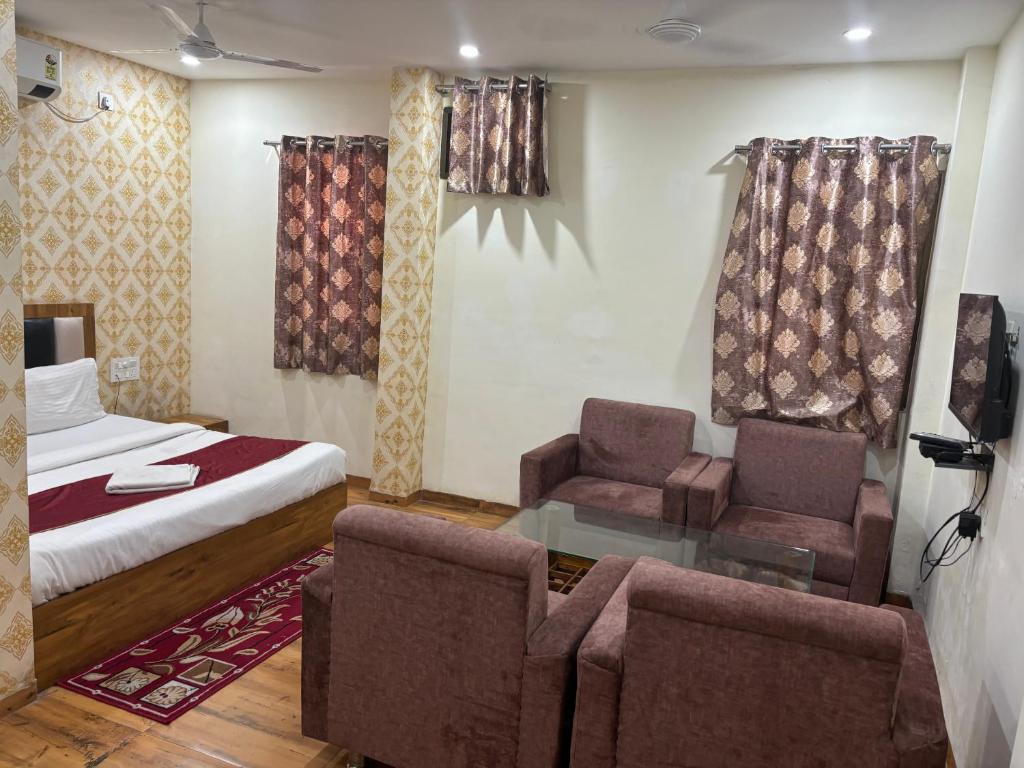 Hotel ARRAJ, Raipur في رايبور: غرفة نوم بسرير واريكة وكراسي