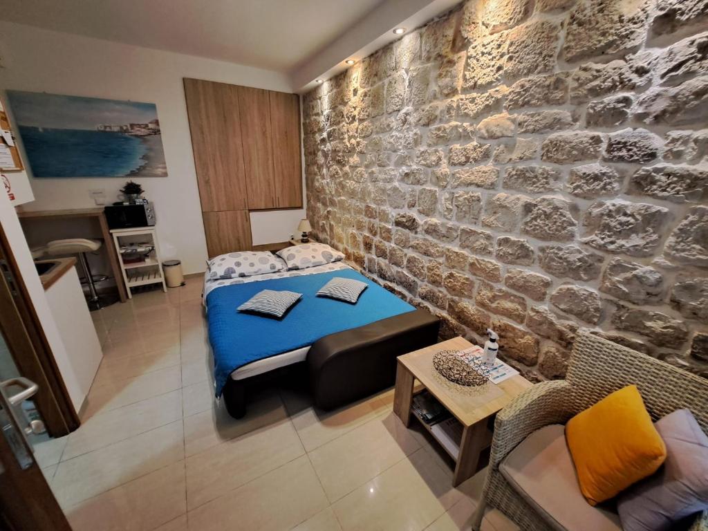 a bedroom with a bed and a stone wall at Studio Apartment Legcevic in Kaštela