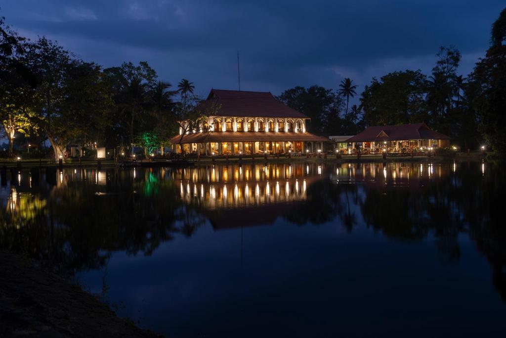 duży budynek z oświetleniem na wodzie w nocy w obiekcie Taj Kumarakom Resort and Spa Kerala w mieście Kumarakom