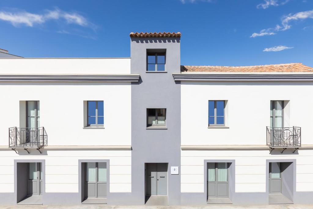 um edifício branco com um céu azul ao fundo em Domu Qirat - Authentic Rooms & Terraces em Tortolì