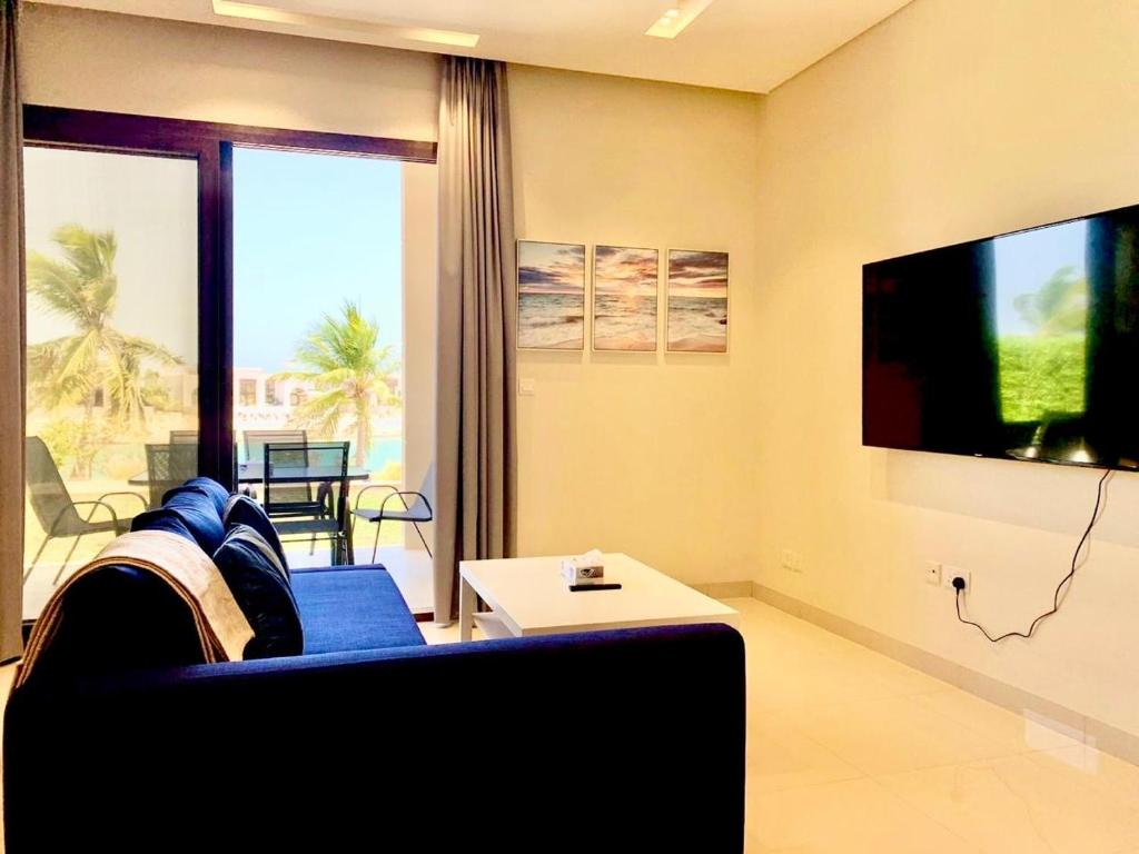 a living room with a blue couch and a tv at Lake View Luxury Suite, Hawana Resort in Salalah