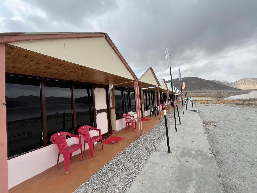 a row of red chairs sitting outside of a building at Padma Cottage Pangong in Spangmik