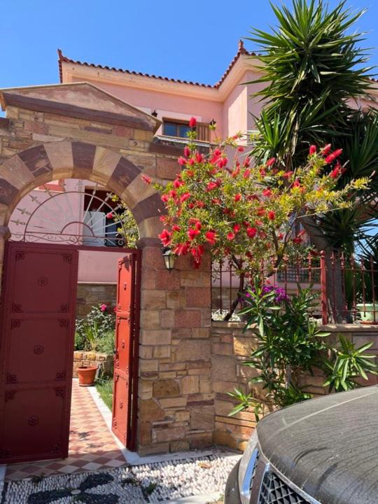a brick building with a red door and flowers at Kampos Apartment in Chios