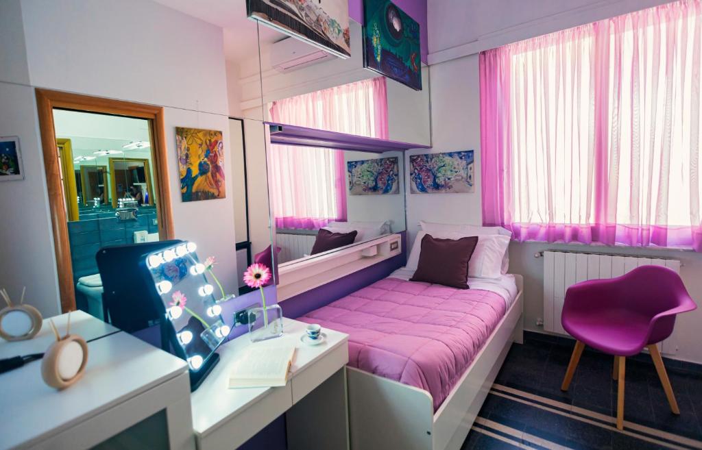 una piccola camera con letto rosa e scrivania di B&B degli Artisti a Palmi