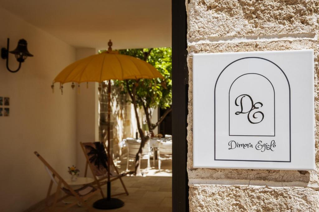 a picture of a door with an umbrella and a chair at Dimora EgiLò in Nardò