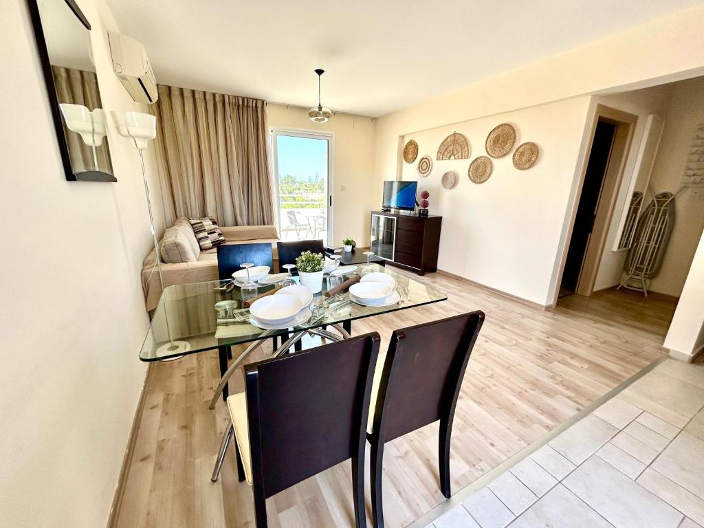 uma sala de estar com uma mesa de vidro e cadeiras em Nissi 3 C14 Sea View Top Floor Apartment em Agia Napa
