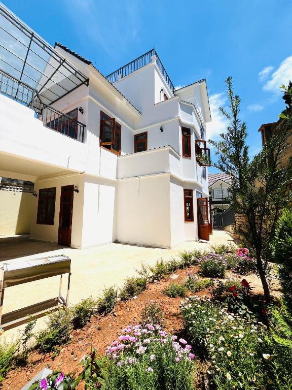 a white house with a bench in a garden at NHỚ House Đà Lạt V in Da Lat