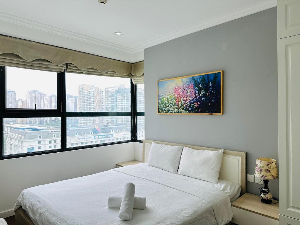 um quarto com uma cama branca e uma grande janela em HKG-Căn hộ Cầu Giấy em Hanói