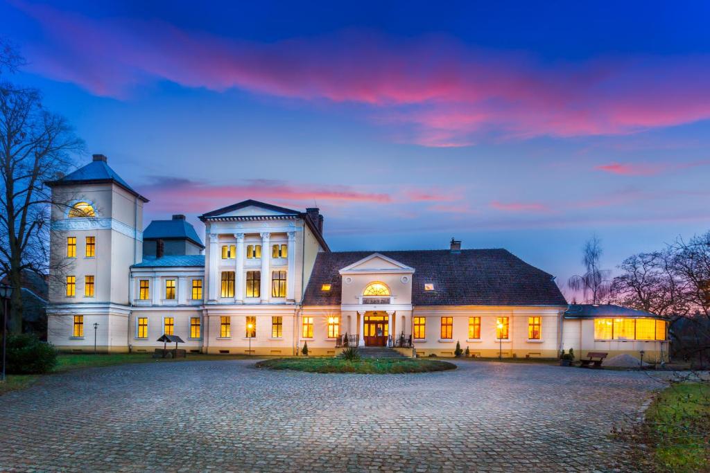 un gran edificio blanco con una torre de reloj. en Pałac Jabłonowo, en Ujście