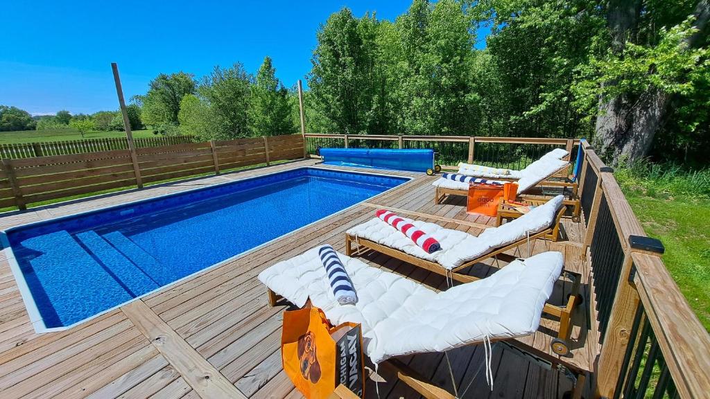a pool with chaise lounges on a wooden deck next to at Meadow Sunrise in Bridgman