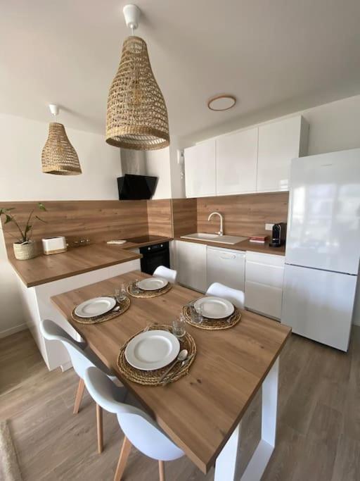 une cuisine avec une table en bois et des chaises ainsi qu'une cuisine avec des placards blancs dans l'établissement Appartement - Visitez Paris, à Aubervilliers