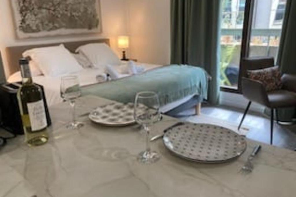 Cette chambre comprend un lit et une table avec des verres à vin. dans l'établissement Le Bonlieu 3 - Joli studio avec balcon en plein coeur de la ville, à Annecy