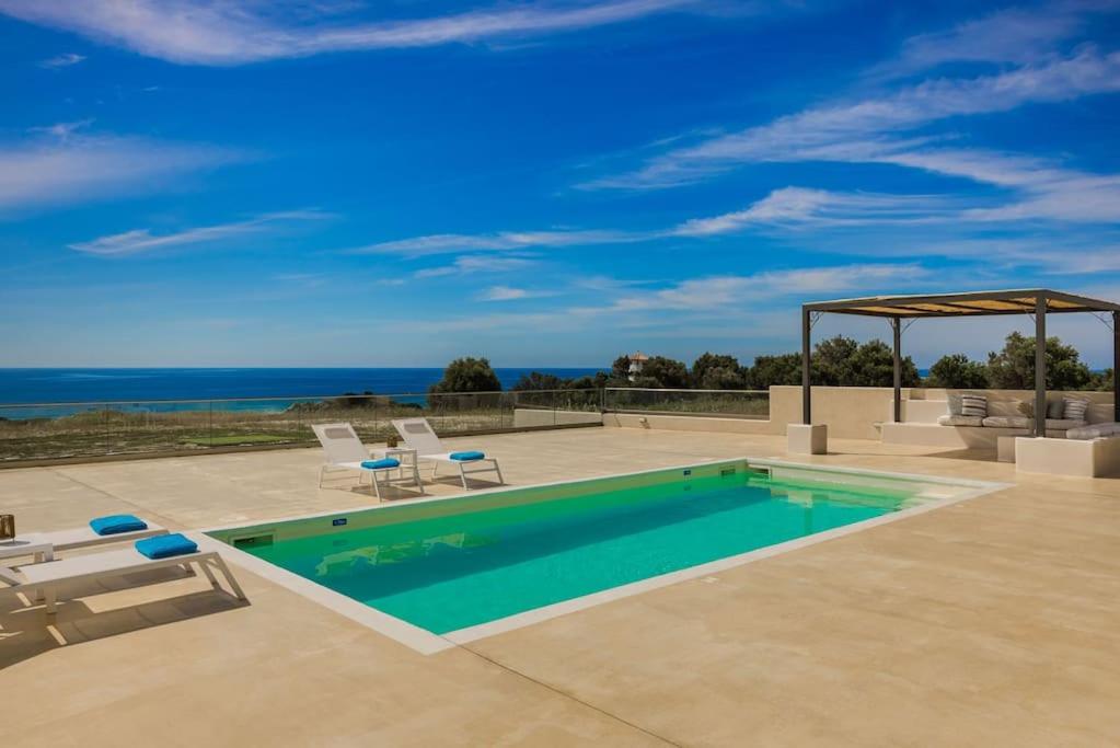 a swimming pool with chairs and a view of the ocean at Villa Lotus - Ionian Villa Collection in Lixouri