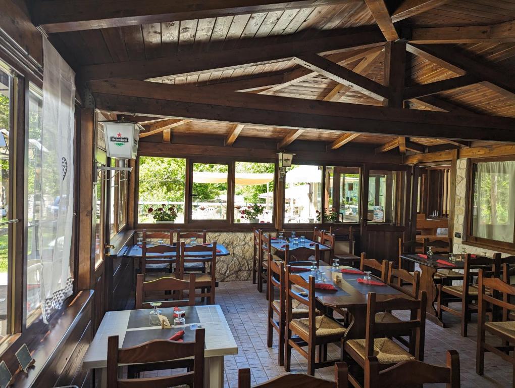 restauracja z drewnianymi stołami, krzesłami i oknami w obiekcie Hotel il Rifugio del Lupo scanno w mieście Scanno