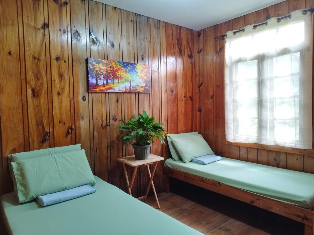 2 camas en una habitación con paredes de madera en Rm 204 Mhapiya-aw Pensione Inn, en Sagada