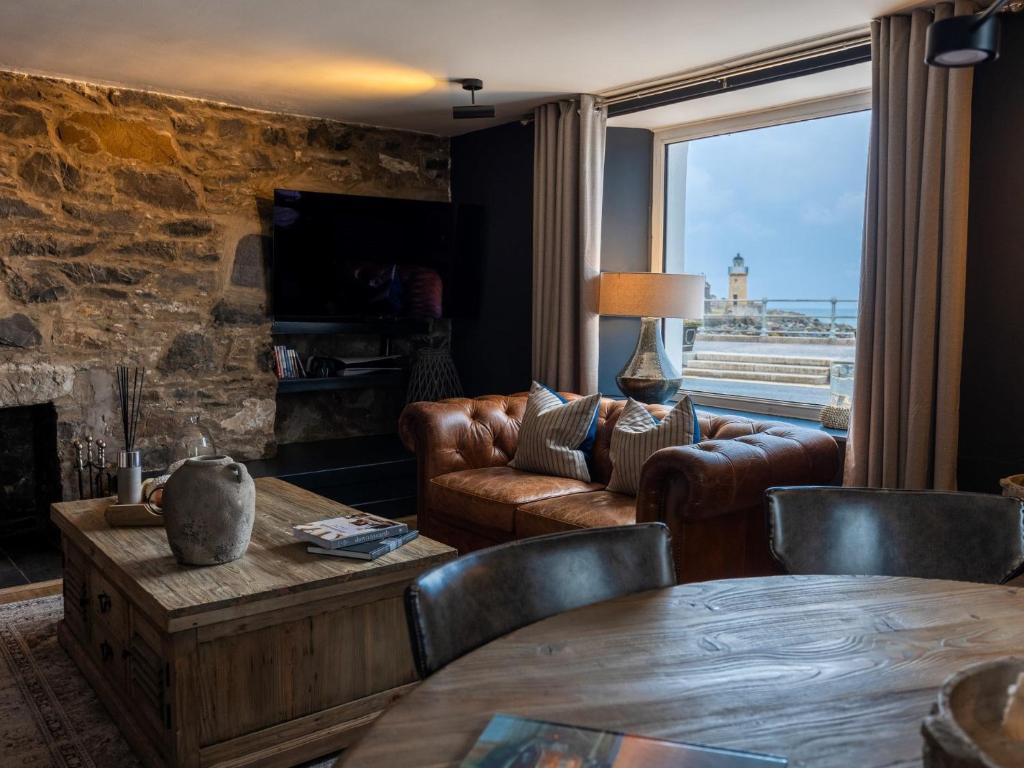 een woonkamer met lederen meubels en een stenen muur bij 3 Bed in Portpatrick 77308 in Portpatrick