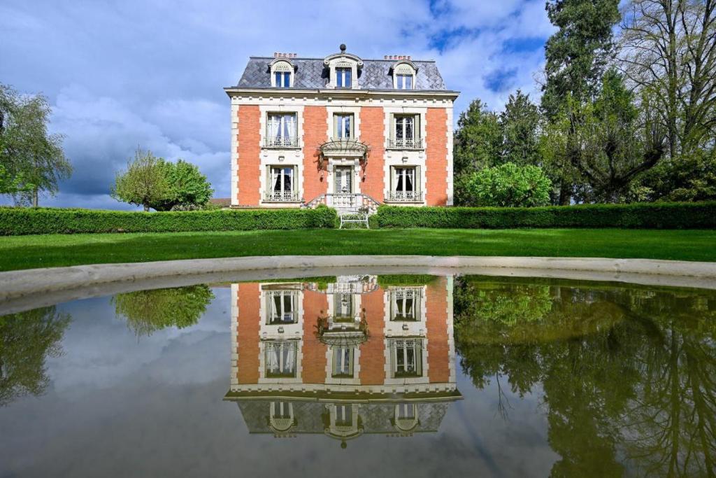 an old house with its reflection in a pond at Château de la Chaix in Saint-Christophe-en-Brionnais