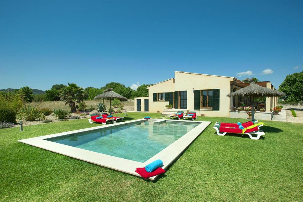 a backyard with a pool with lawn chairs and a house at Villa Figueral by Villa Plus in Alcudia