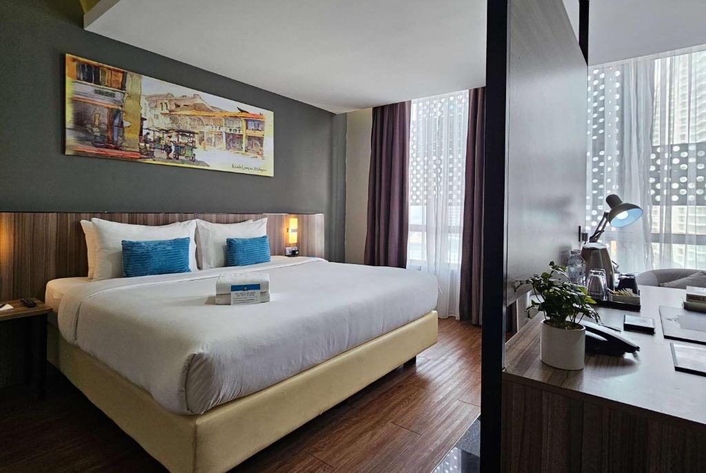 um quarto de hotel com uma cama grande e uma secretária em Days Hotel & Suites by Wyndham Fraser Business Park KL em Kuala Lumpur