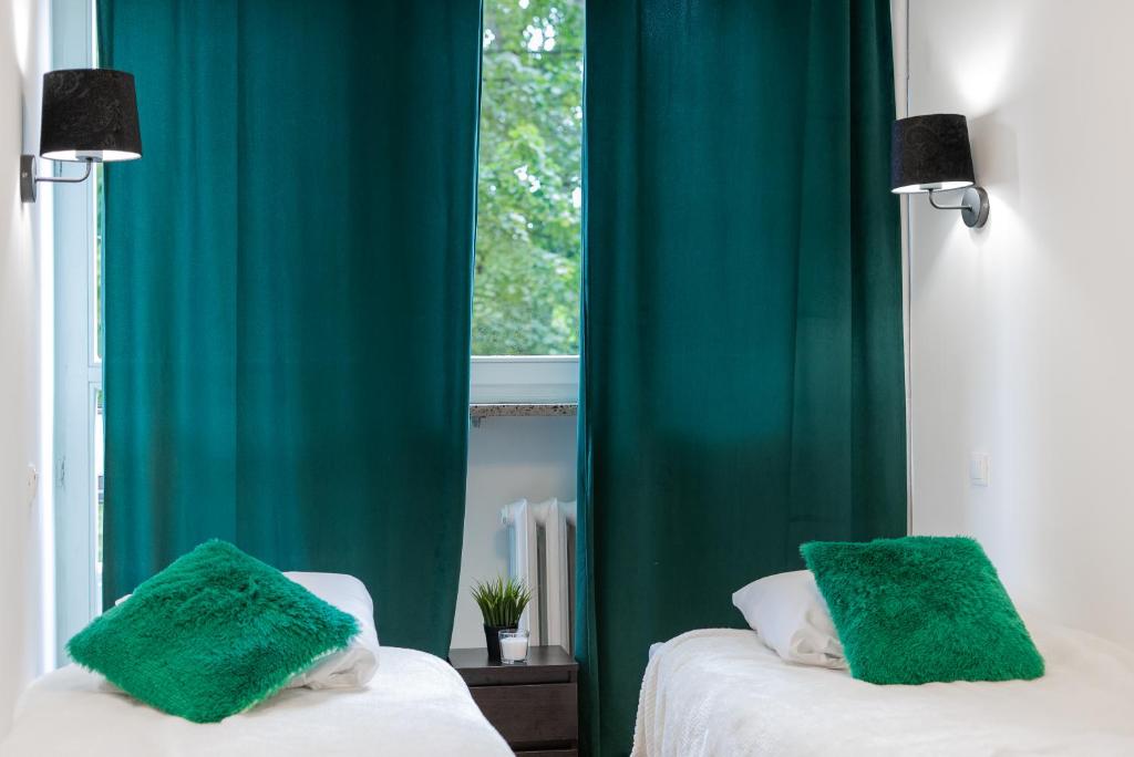 2 łóżka w pokoju z zielonymi zasłonami w obiekcie MGR Pokoje w samym Centrum Warszawy by Metro Rondo ONZ - SUPER Bed Year23 w Warszawie