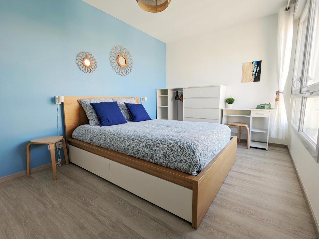een slaapkamer met een bed en een blauwe muur bij Au 4 le long du canal avec Parking in Dijon