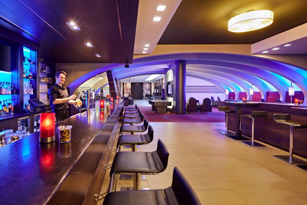 a man standing at a bar in a restaurant at Lindner Hotel Nurburgring Congress, part of JdV by Hyatt in Nürburg