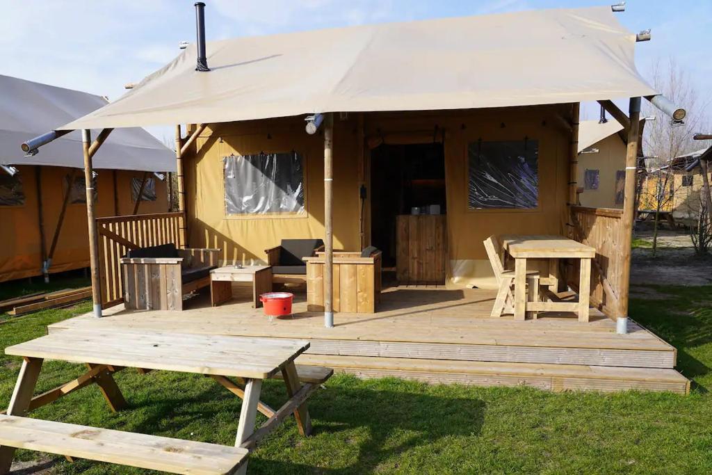 een grote tent met een tafel en een picknicktafel bij Glamping met bar en privé sanitair voor 5 Personen Sneezy in Behelp