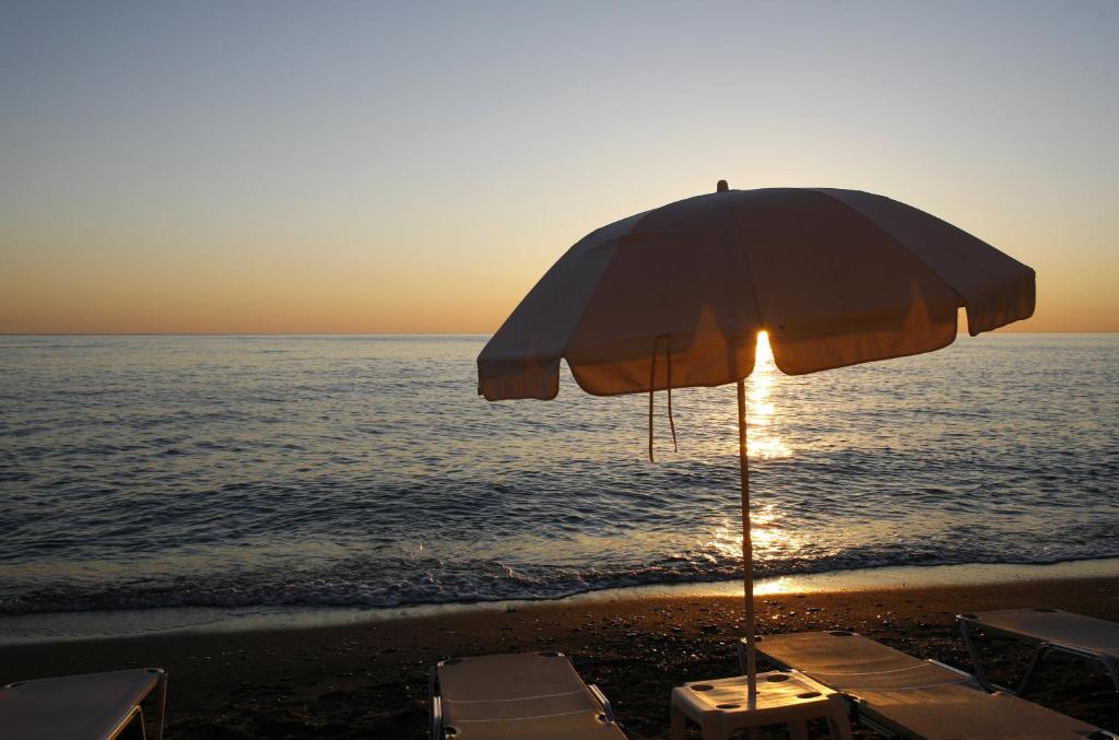 a beach with an umbrella and chairs and the ocean at Glaros Beach Hotel in Hersonissos