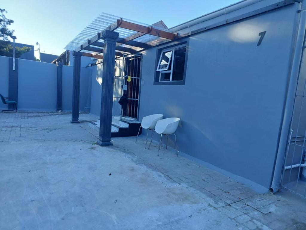 a patio with two chairs and a blue building at Freedommedia guesthouse in Gqeberha