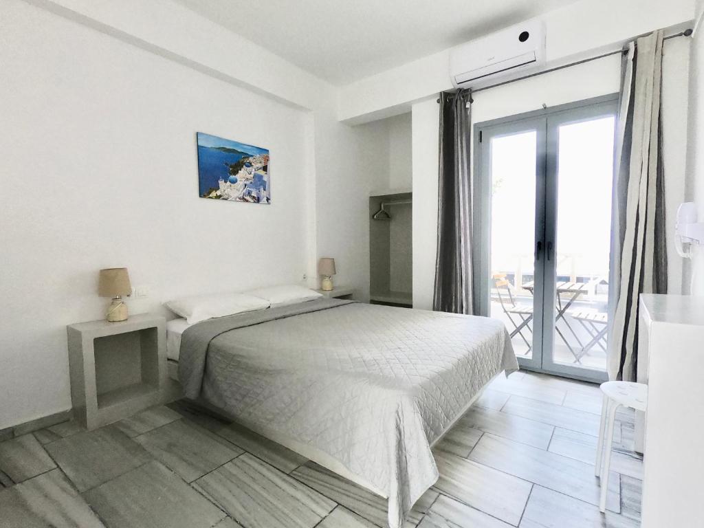 a white bedroom with a bed and a balcony at Anny Studios & Rooms Perissa Beach in Perissa