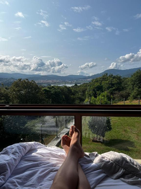 a person laying in bed looking out a window at O MIRADOR da RÍA in Outes