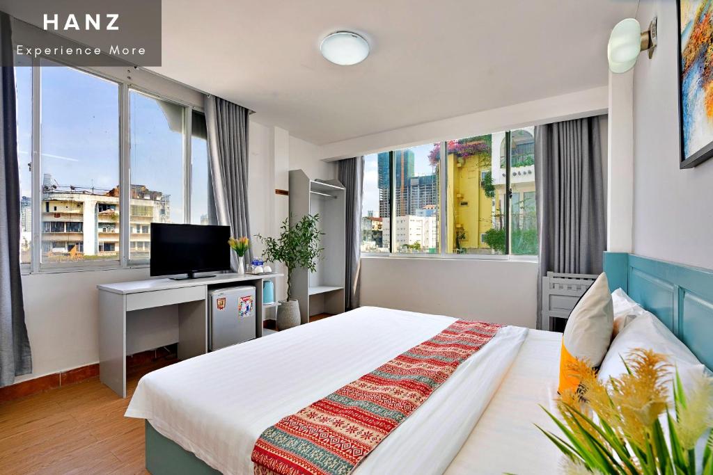 胡志明市的住宿－HANZ Hotel upstair MPChill，一间卧室配有一张床和一张书桌及电视