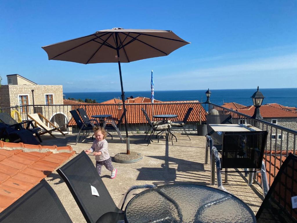 a little girl standing under an umbrella on a patio at Apartments Gusar in Ulcinj