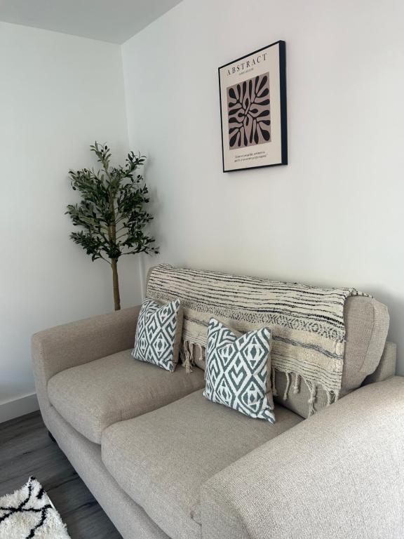 - un canapé dans un salon avec un arbre sur le mur dans l'établissement Free Parking! Comfy home in Barwell, Leicester -c-, 