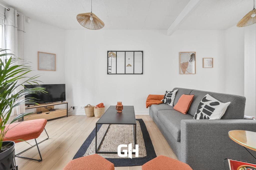 a living room with a gray couch and a tv at Les Arômes - Maison avec jardin 8 pers Paris in Maisons-Alfort