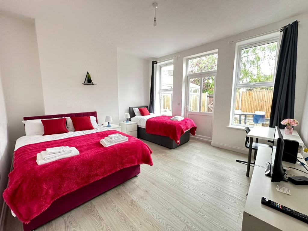 1 dormitorio con 2 camas con sábanas rojas y escritorio en Wonderful 2 bed flat in the Bedford town centre, en Bedford