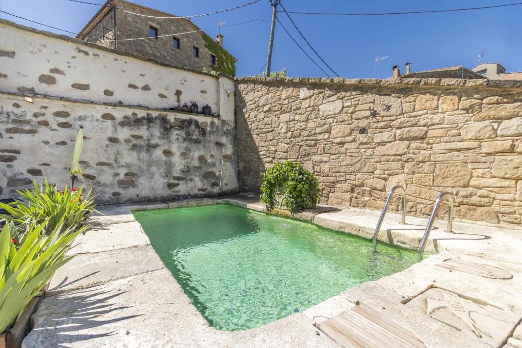 una pequeña piscina de agua junto a una pared de piedra en Les Orenetes en Artesa de Segre