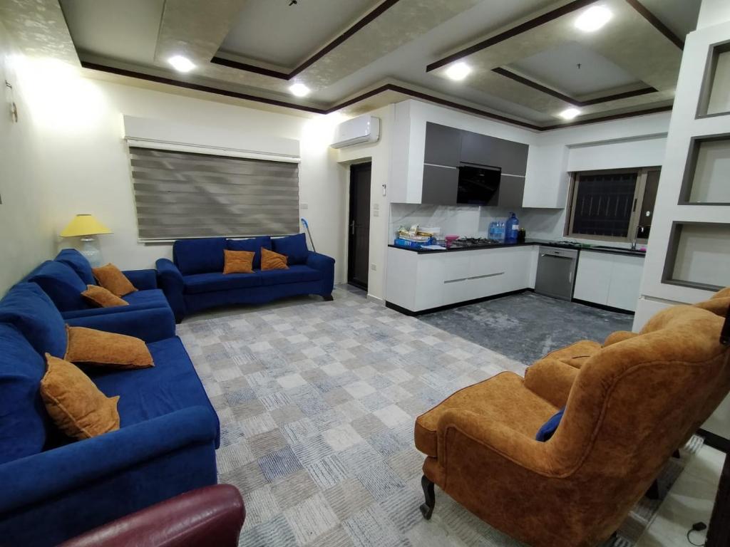 a living room with a blue couch and two chairs at زريقات للشقق المفروشه in Irbid