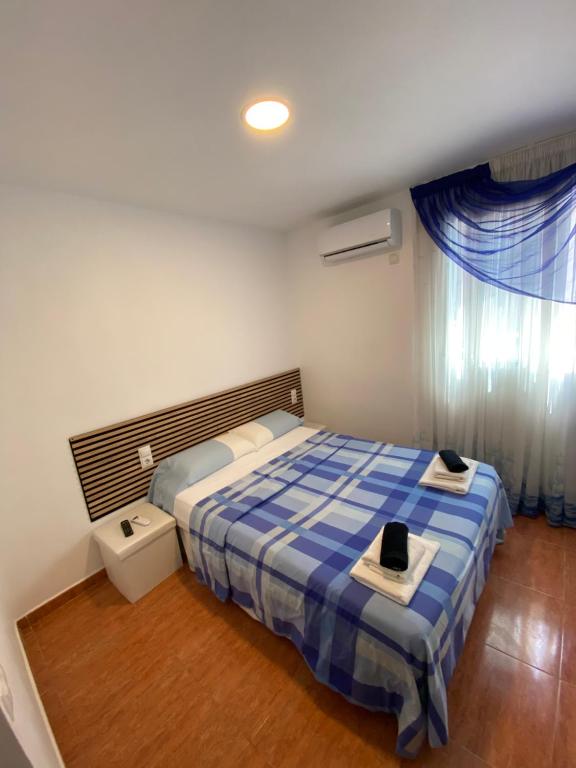 a bedroom with a bed with a blue and white comforter at Habitaciones con baño y cocina privada in Valencia