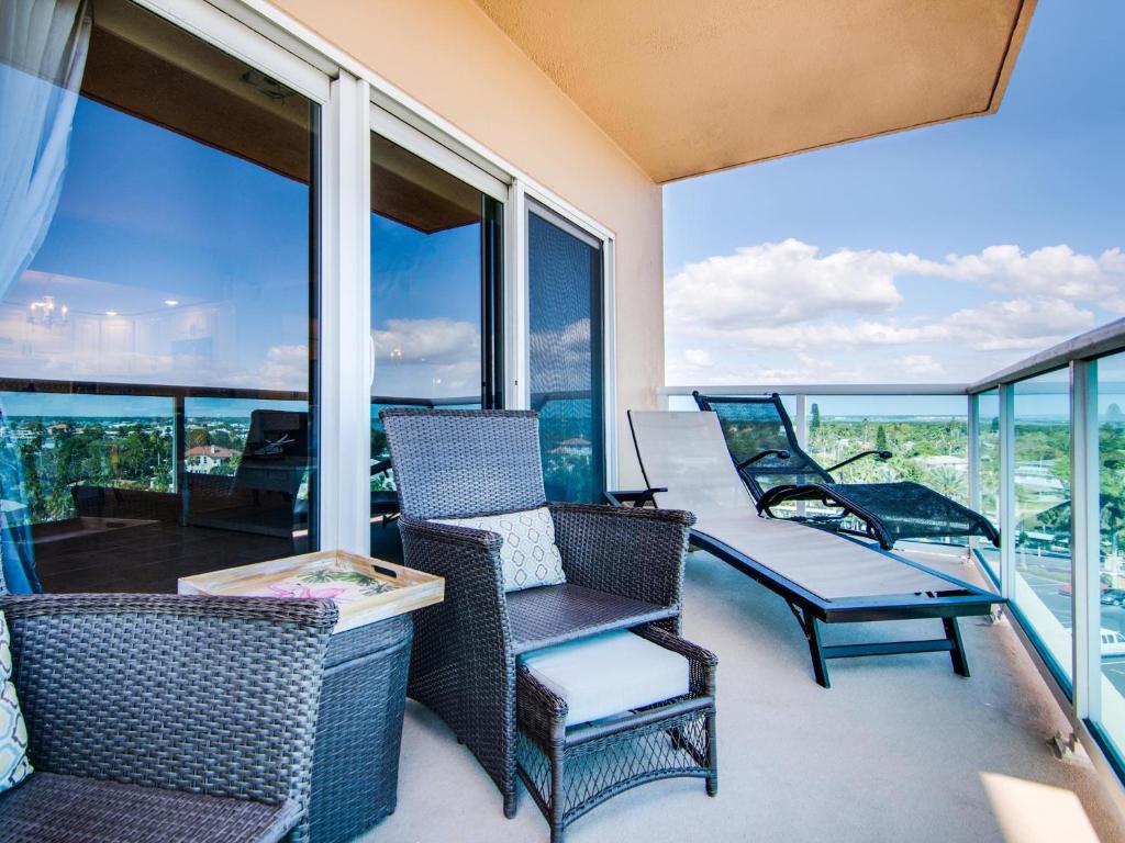 balcón con sillas, mesas y ventanas en Regatta Beach Club S614, en Clearwater Beach