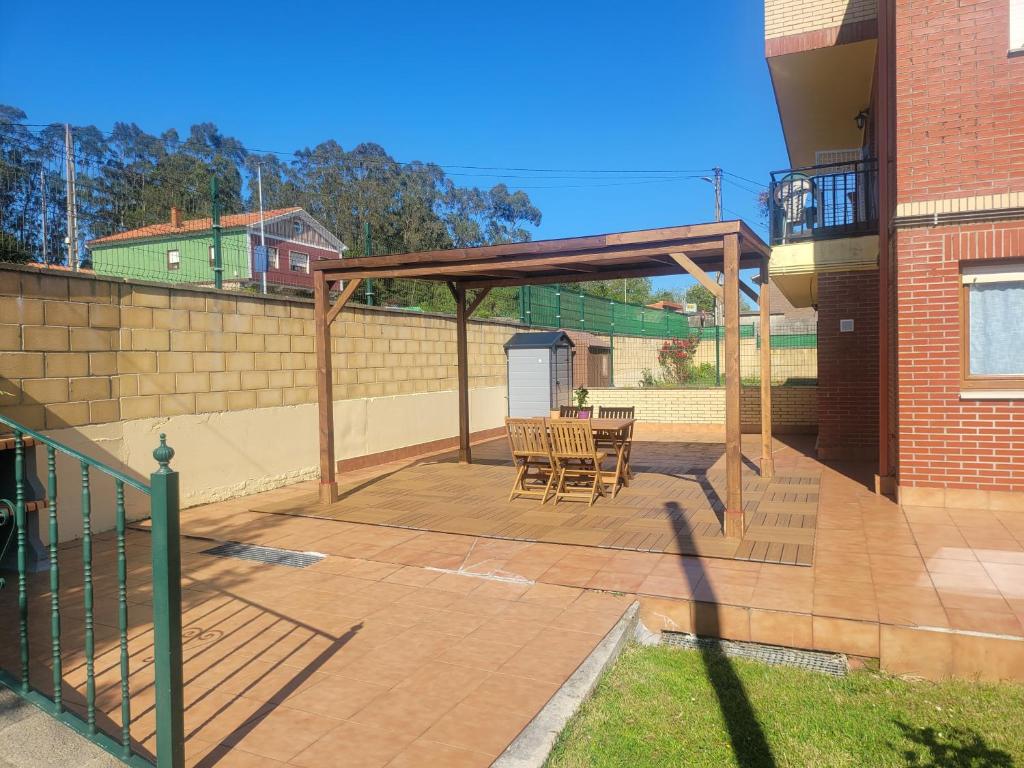 a patio with a wooden pergola and a table at Precioso Bajo con Jardin y Parking in Miengo